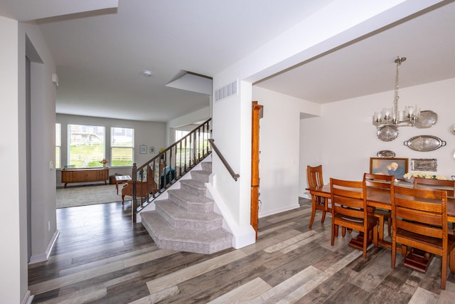 dining room featuring baseboards, a chandelier, stairs, visible vents, and wood finished floors