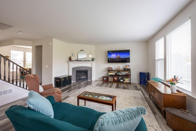 living room featuring a fireplace, stairs, wood finished floors, and a healthy amount of sunlight