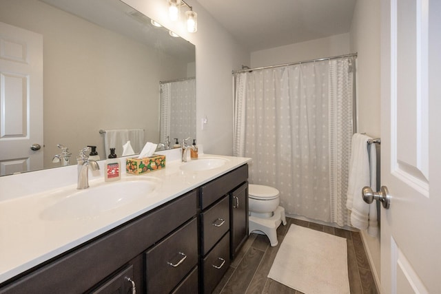 bathroom with a sink, toilet, double vanity, and wood finished floors