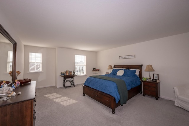 bedroom with light carpet, multiple windows, and baseboards