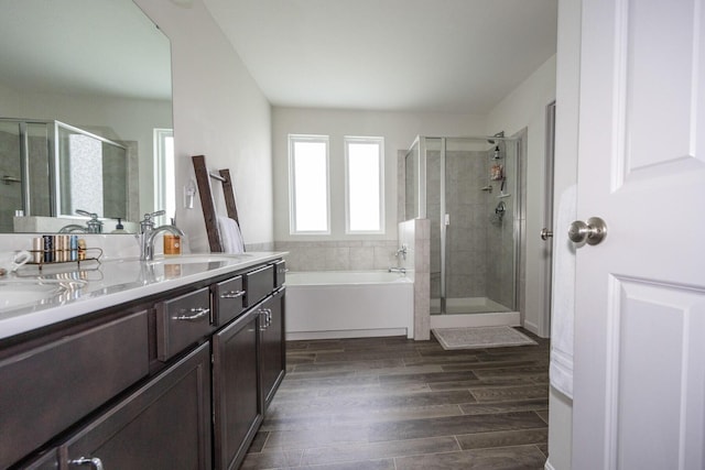 bathroom with a sink, a bath, a shower stall, and double vanity