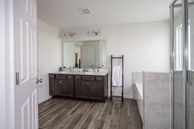 full bath with a sink, visible vents, a garden tub, and wood tiled floor