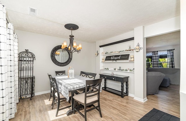 dining area with visible vents, baseboards, an inviting chandelier, a textured ceiling, and light wood finished floors