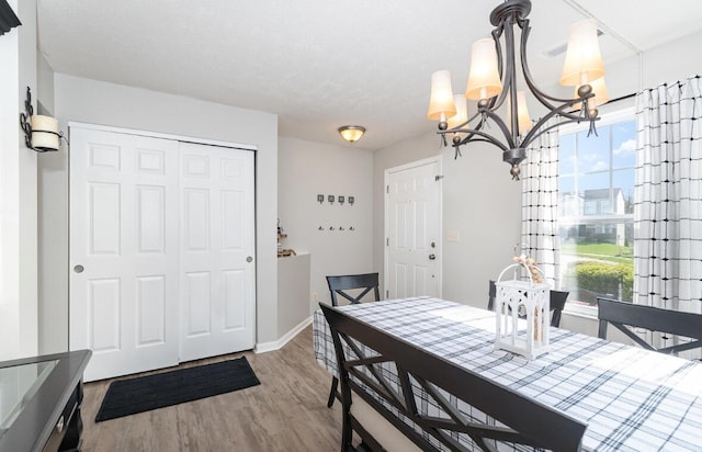 dining area featuring a chandelier, wood finished floors, baseboards, and plenty of natural light