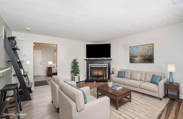 living room with wood finished floors, baseboards, and a warm lit fireplace