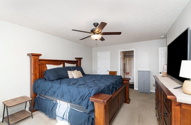 bedroom with ceiling fan, light colored carpet, baseboards, and ensuite bath