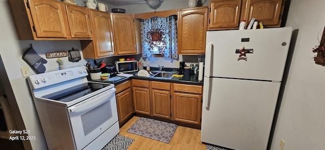 kitchen featuring white appliances, dark countertops, light wood-style floors, brown cabinets, and a sink