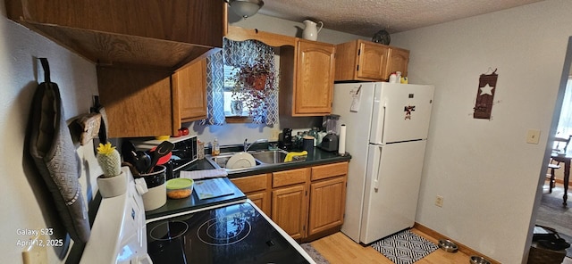 kitchen featuring plenty of natural light, a sink, freestanding refrigerator, and dark countertops
