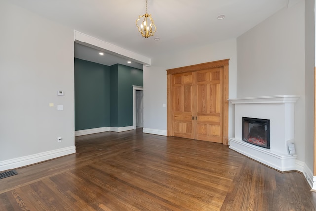 224 Wallace Ave, Covington, KY 41014 - unfurnished living room featuring baseboards, visible vents, an inviting chandelier, a glass covered fireplace, and wood finished floors