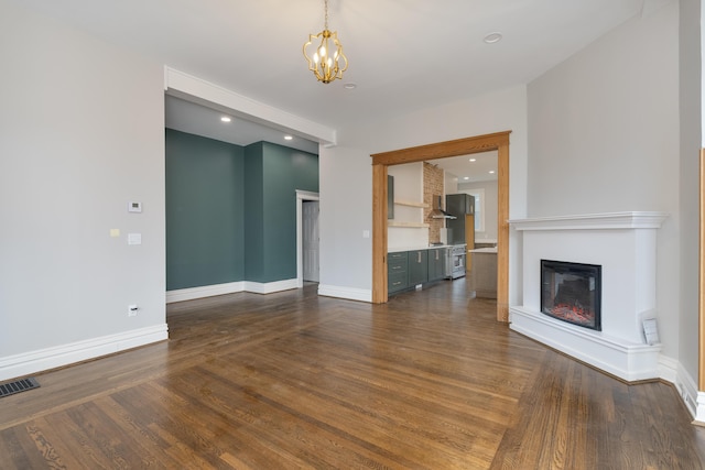 224 Wallace Ave, Covington, KY 41014 - unfurnished living room with a notable chandelier, visible vents, baseboards, a glass covered fireplace, and dark wood-style flooring