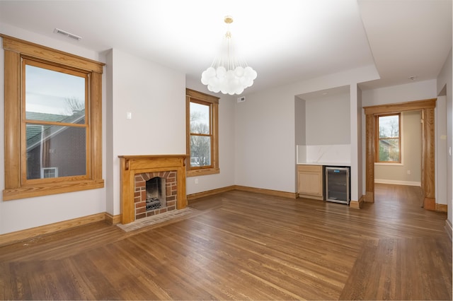 224 Wallace Ave, Covington, KY 41014 - unfurnished living room with a fireplace with flush hearth, beverage cooler, an inviting chandelier, visible vents, and baseboards