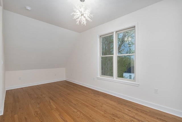 224 Wallace Ave, Covington, KY 41014 - empty room with baseboards, vaulted ceiling, wood finished floors, and an inviting chandelier