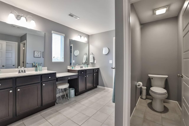 bathroom featuring visible vents, a sink, toilet, two vanities, and tile patterned floors