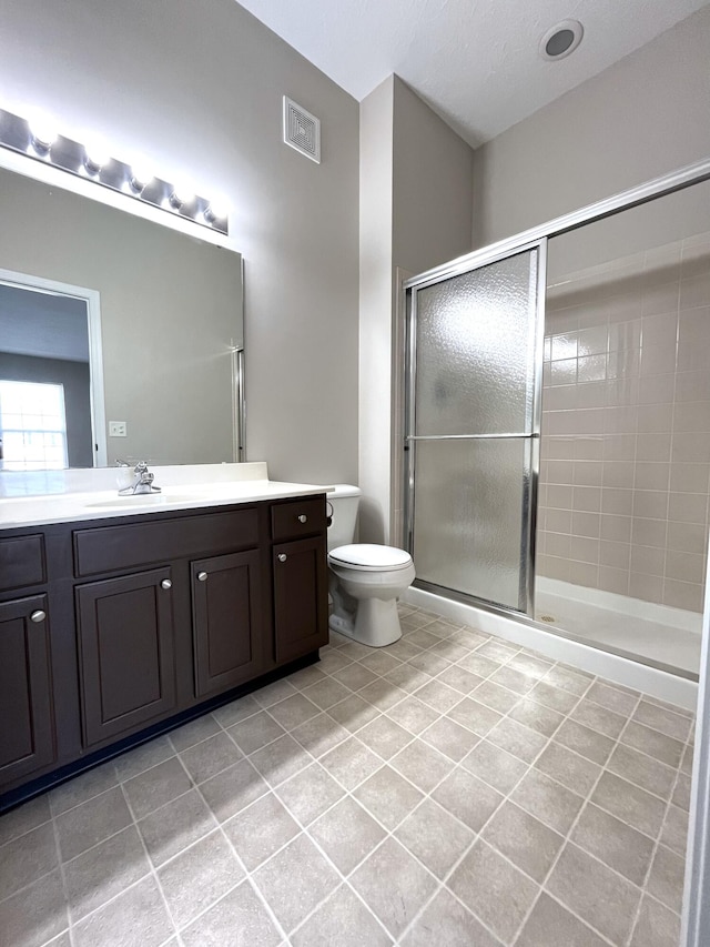 full bathroom featuring a shower stall, vanity, visible vents, toilet, and tile patterned floors