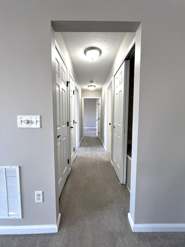 hallway featuring carpet, visible vents, and baseboards