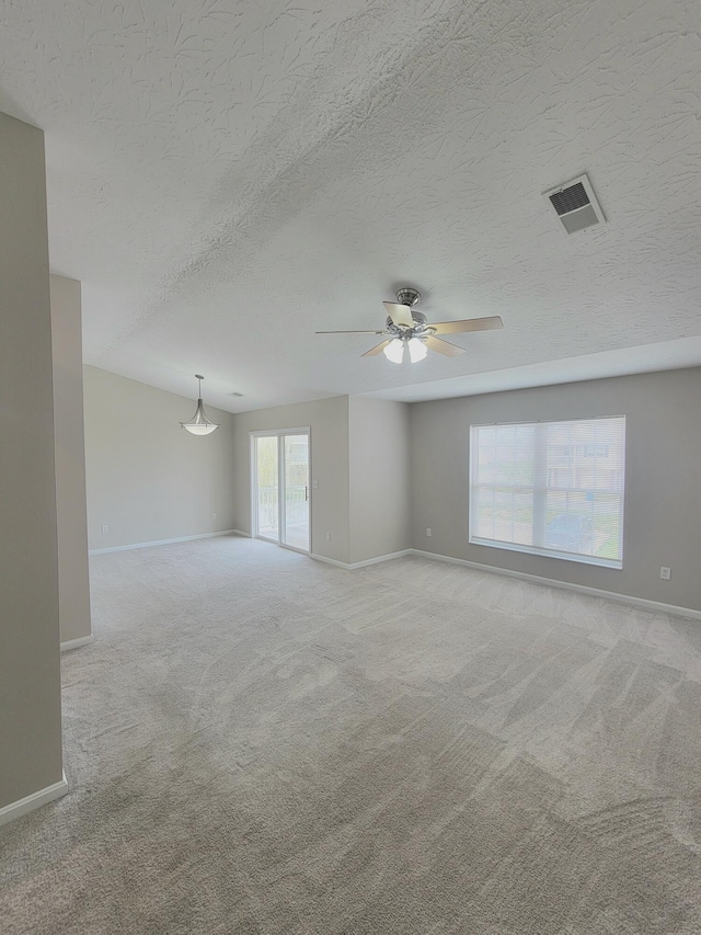 spare room featuring carpet flooring, visible vents, baseboards, and a ceiling fan