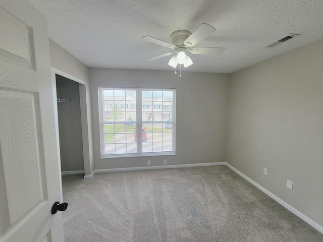 carpeted spare room featuring baseboards, a ceiling fan, and visible vents