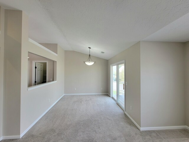 spare room with a textured ceiling, light carpet, and vaulted ceiling