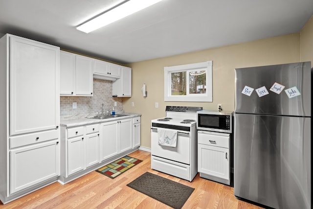 kitchen with white cabinets, a sink, light countertops, appliances with stainless steel finishes, and light wood-type flooring