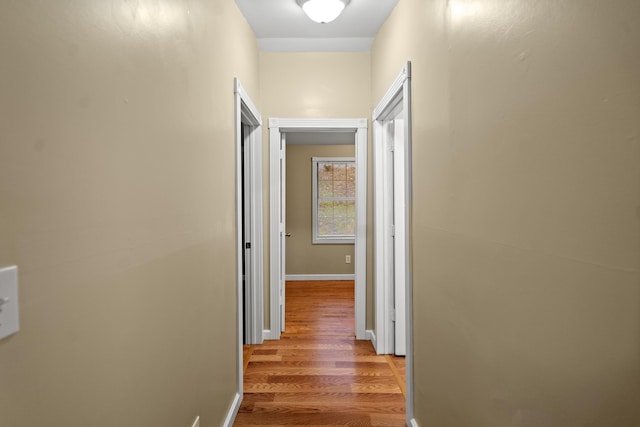 corridor featuring light wood-type flooring and baseboards