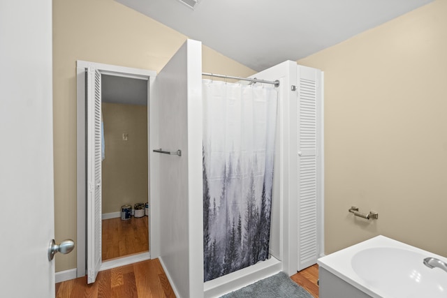 full bath featuring curtained shower, wood finished floors, and lofted ceiling