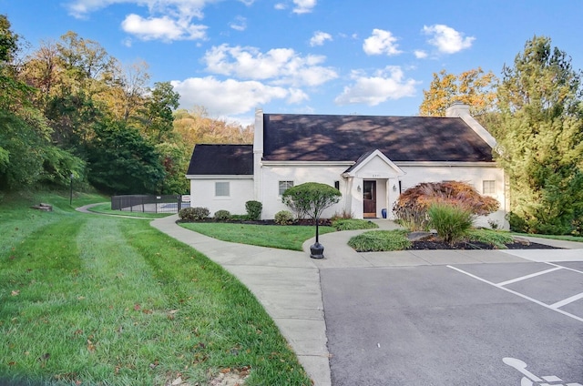 view of front of house with a chimney, roof with shingles, and a front yard
