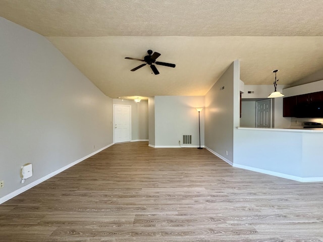 unfurnished living room with ceiling fan, visible vents, wood finished floors, baseboards, and lofted ceiling