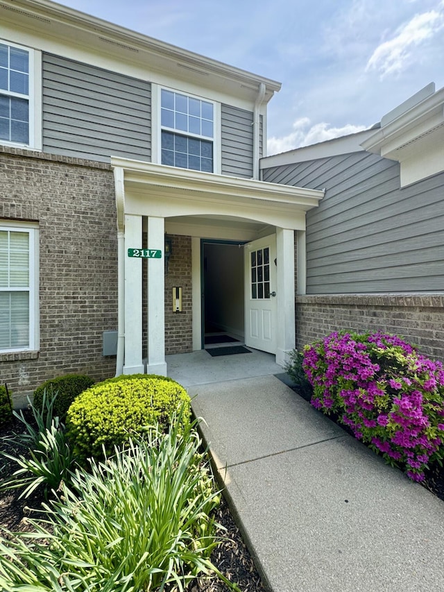 doorway to property with covered porch and brick siding