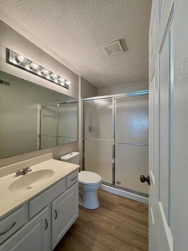 full bathroom featuring vanity, a stall shower, wood finished floors, and visible vents