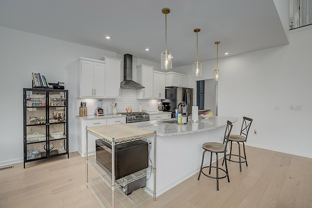 9956 Meadow Glen Dr, Independence, KY 41051 - kitchen with white cabinets, a sink, wall chimney range hood, appliances with stainless steel finishes, and light wood-style floors