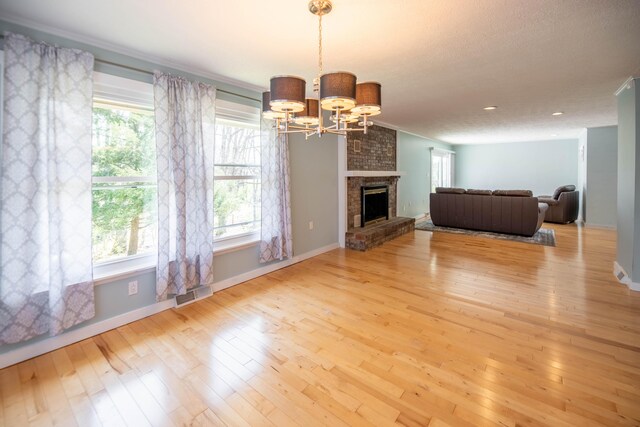 living area with visible vents, plenty of natural light, a notable chandelier, and hardwood / wood-style flooring