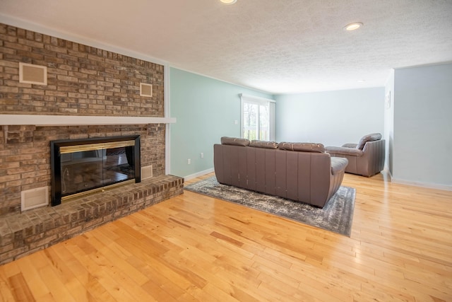 living room featuring baseboards, a textured ceiling, wood finished floors, and a fireplace