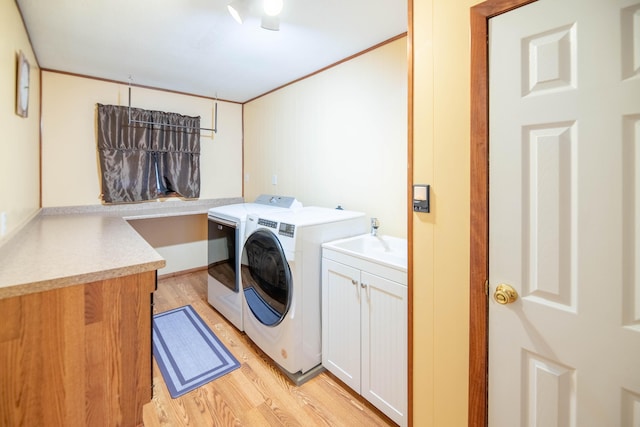 washroom with light wood-style flooring, cabinet space, and washer and dryer
