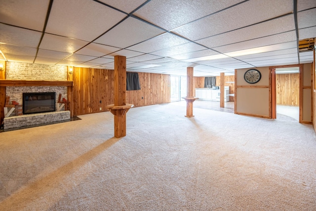 below grade area with carpet floors, wood walls, a paneled ceiling, and a fireplace