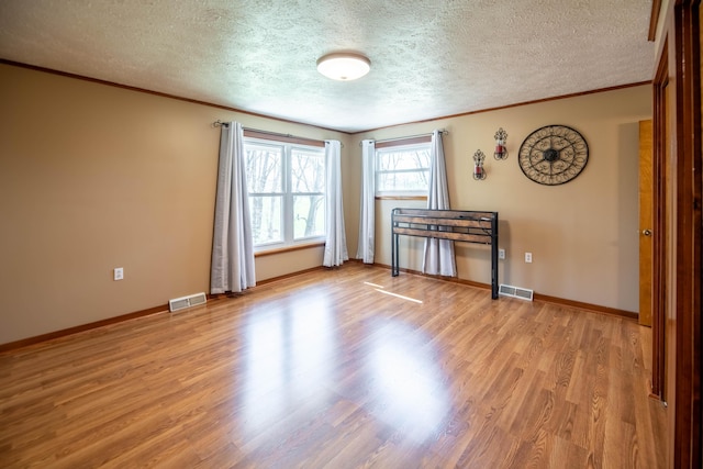 empty room with a textured ceiling, visible vents, and light wood-style flooring