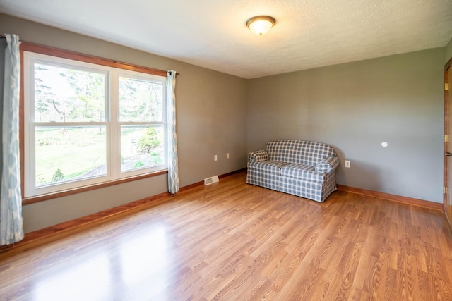sitting room featuring visible vents, light wood finished floors, and baseboards