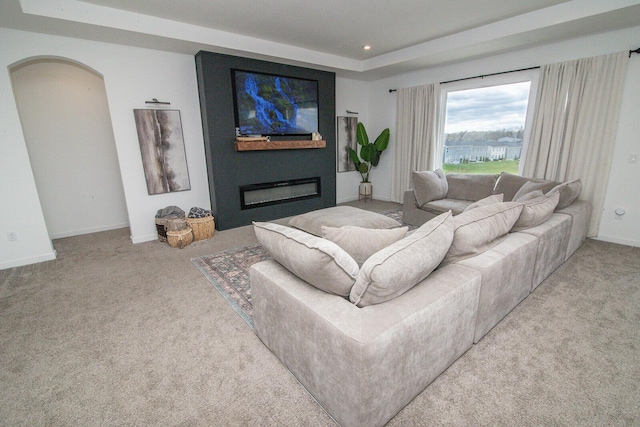 living room featuring carpet floors, recessed lighting, arched walkways, and a glass covered fireplace