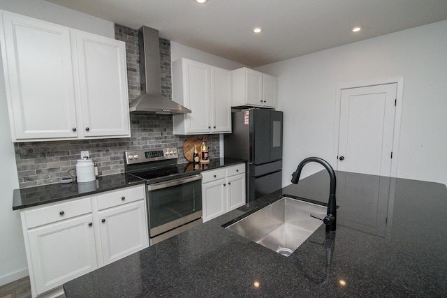 kitchen featuring a sink, wall chimney range hood, stainless steel electric stove, freestanding refrigerator, and decorative backsplash