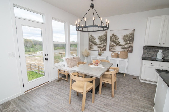 dining area featuring a chandelier, light wood-style flooring, and baseboards