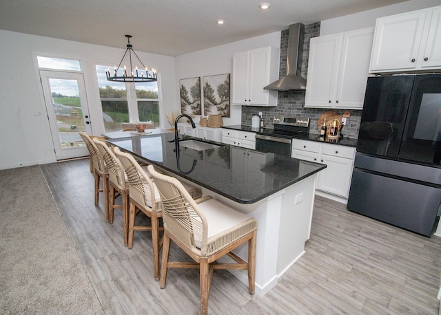 kitchen featuring an inviting chandelier, a sink, wall chimney range hood, stainless steel range with electric cooktop, and smart refrigerator