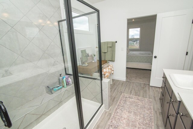 full bath featuring ensuite bathroom, a shower stall, vanity, wood finished floors, and baseboards