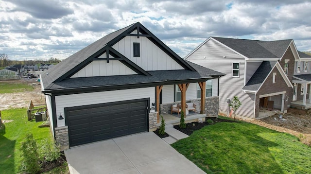 view of front of house featuring board and batten siding, a front yard, stone siding, and covered porch