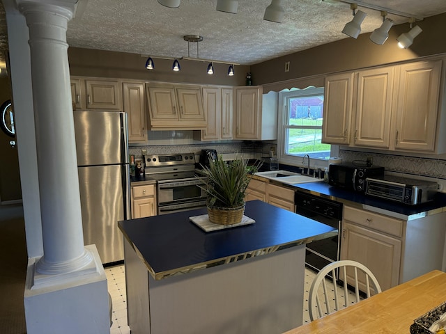 kitchen featuring rail lighting, dark countertops, ornate columns, stainless steel appliances, and a sink