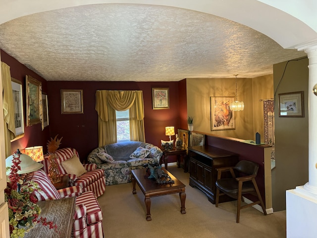 carpeted living room with ornate columns, a notable chandelier, and a textured ceiling