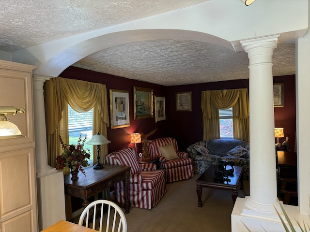 carpeted living room featuring decorative columns, plenty of natural light, and a textured ceiling