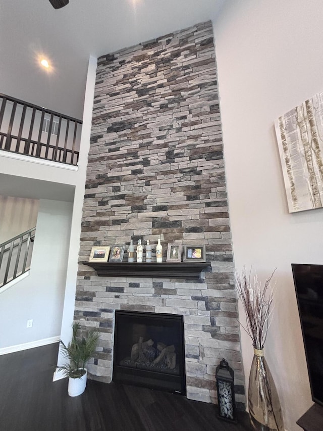 details with wood finished floors, baseboards, and a stone fireplace