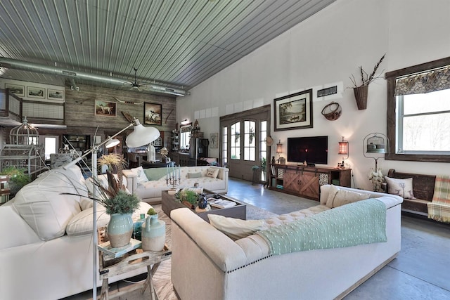 living area featuring wooden walls, concrete flooring, and a high ceiling