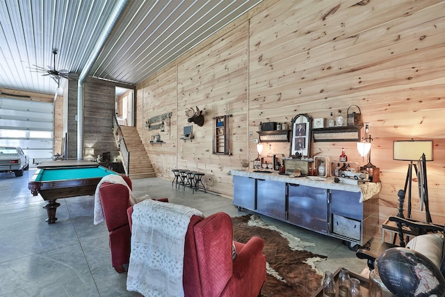 interior space with concrete flooring, billiards, and wooden walls