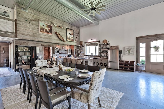 dining room featuring ceiling fan, a high ceiling, and finished concrete floors