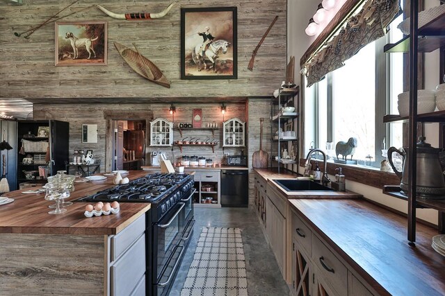 kitchen featuring black appliances, a towering ceiling, butcher block countertops, and a sink